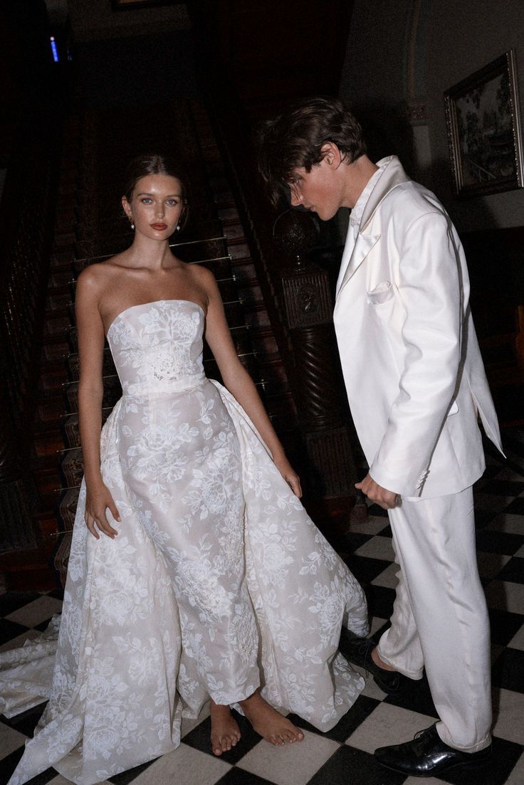 a man and woman in formal wear standing next to each other on a checkered floor