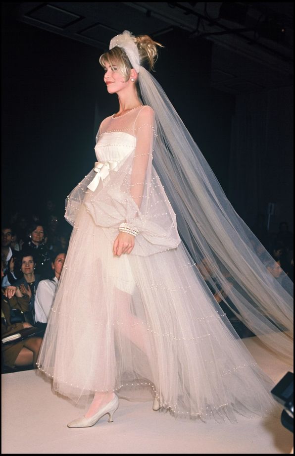 a woman is walking down the runway wearing a wedding dress with long veil on her head