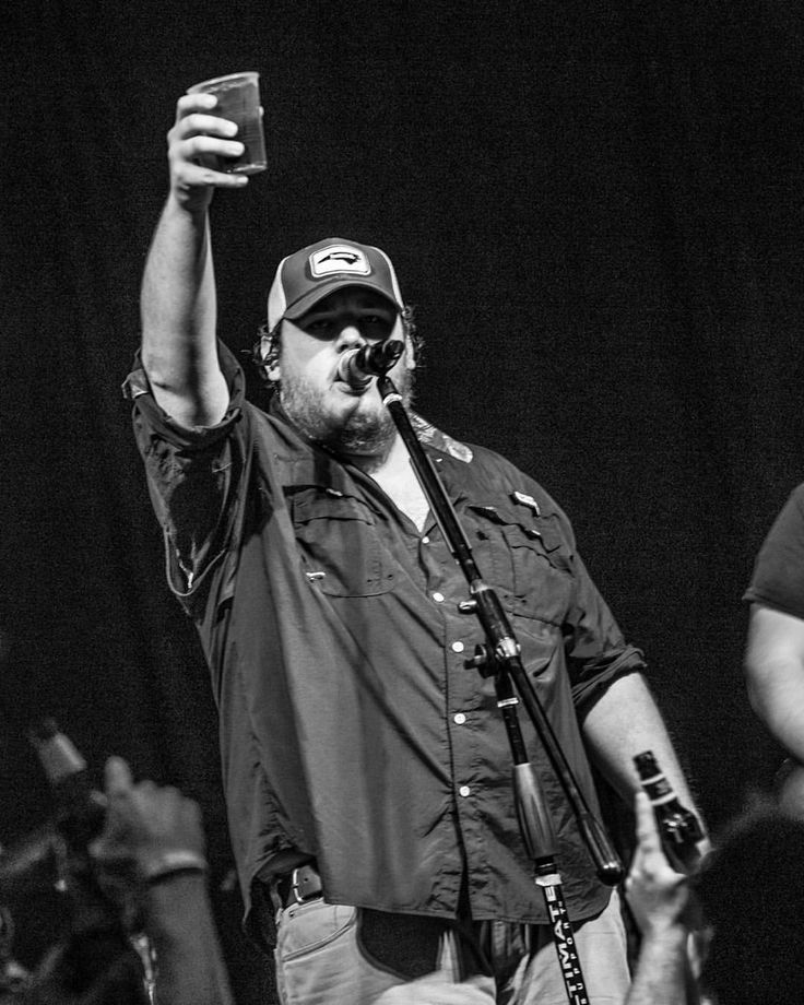 a man holding up a cell phone while standing on stage