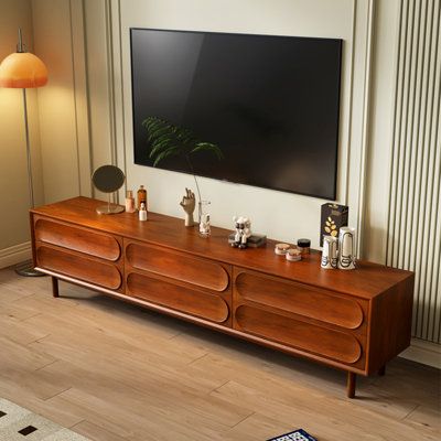 a large flat screen tv mounted to the side of a wooden cabinet in a living room