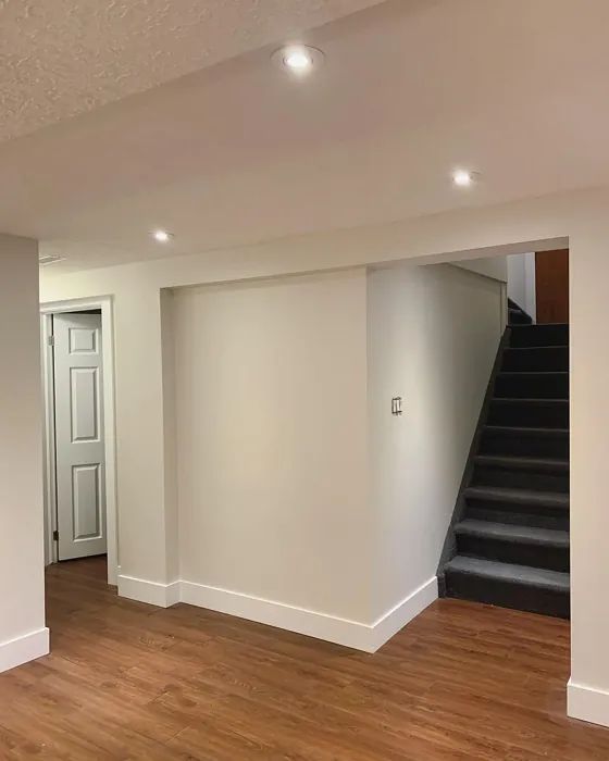 an empty living room with stairs leading up to the second floor and another door in the background