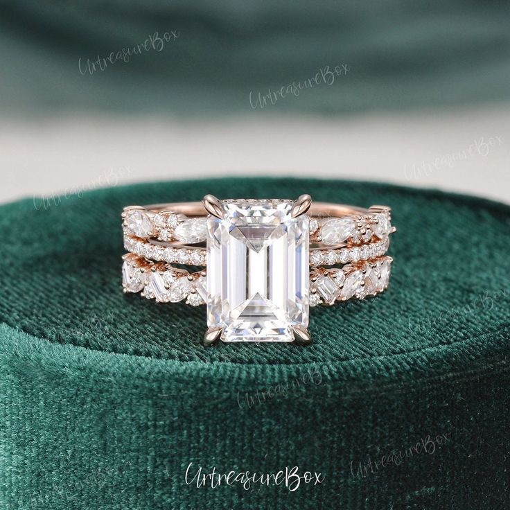 an emerald colored engagement ring set with two bands and a center stone surrounded by diamonds