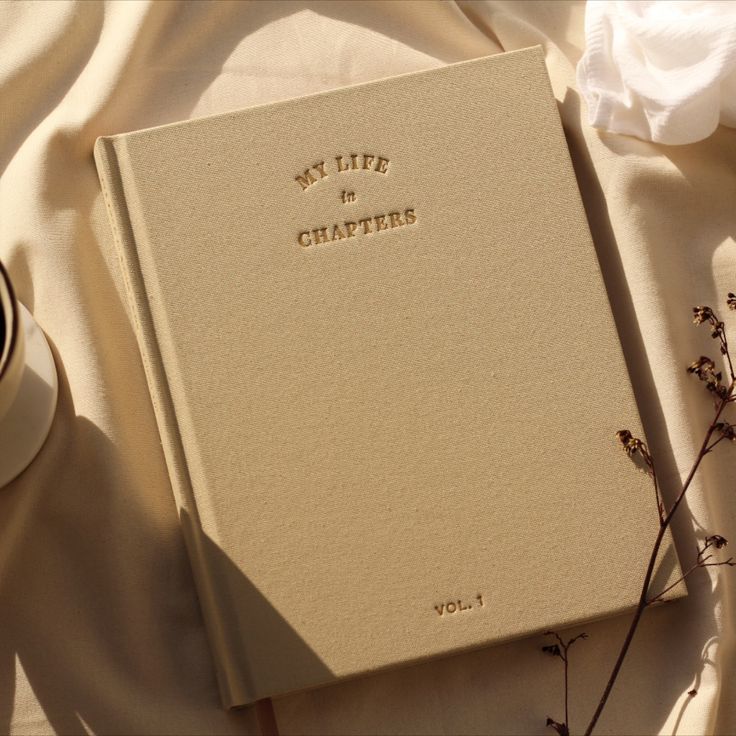 a white book sitting on top of a table next to a cup and saucer