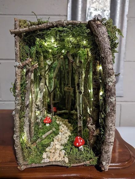 a wooden box with moss and mushrooms in the woods on it's sides, sitting on top of a table