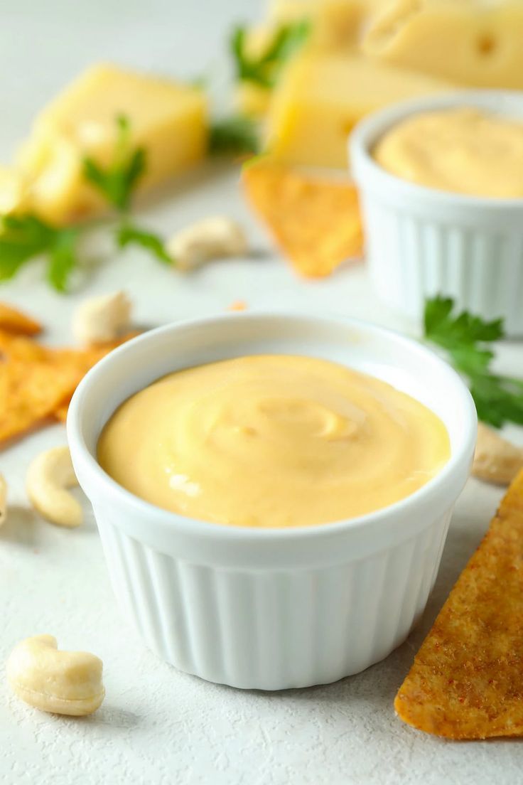 two white bowls filled with dip next to crackers