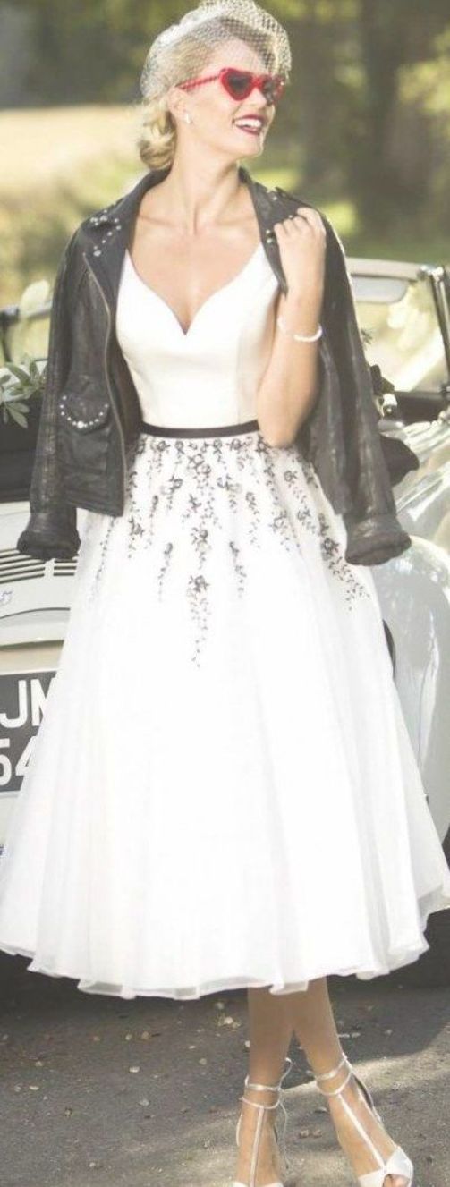 a woman in a white dress and black leather jacket standing next to a vintage car