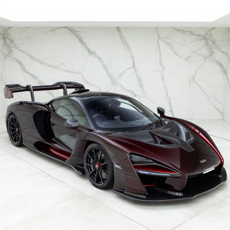 a red and black sports car parked in a room with marble walls on the side