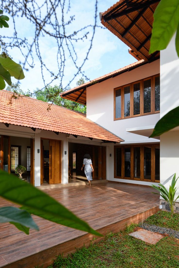 a person walking into a house with wooden floors and doors on the outside, surrounded by greenery