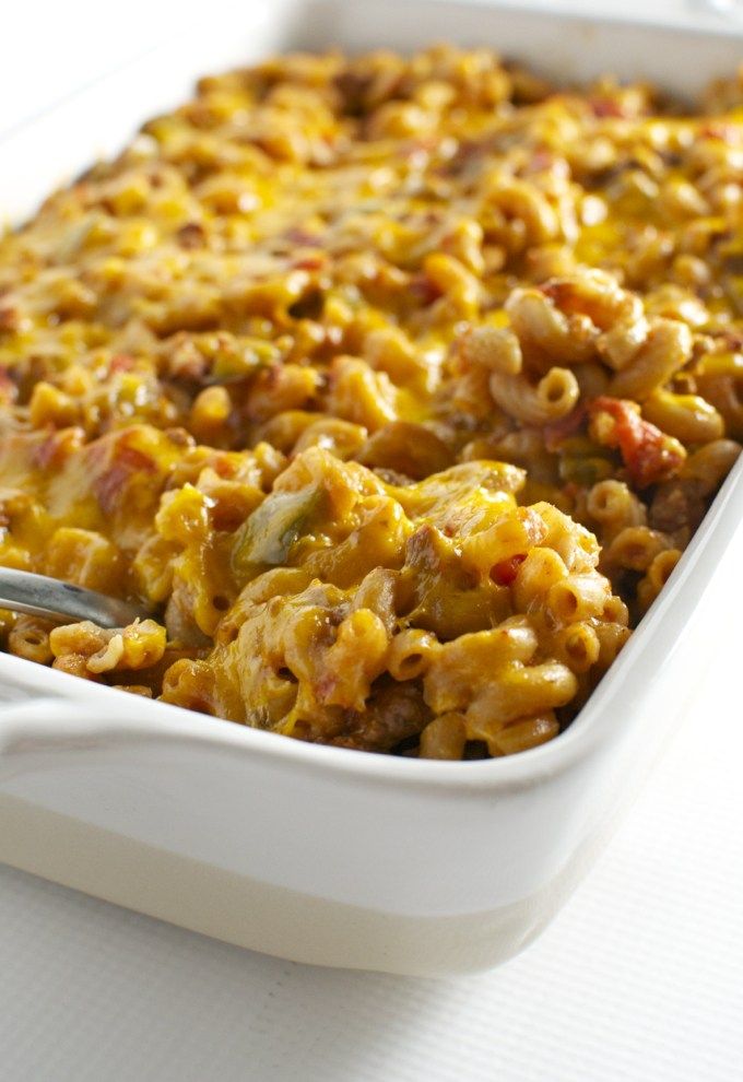 a white casserole dish filled with macaroni, cheese and meats