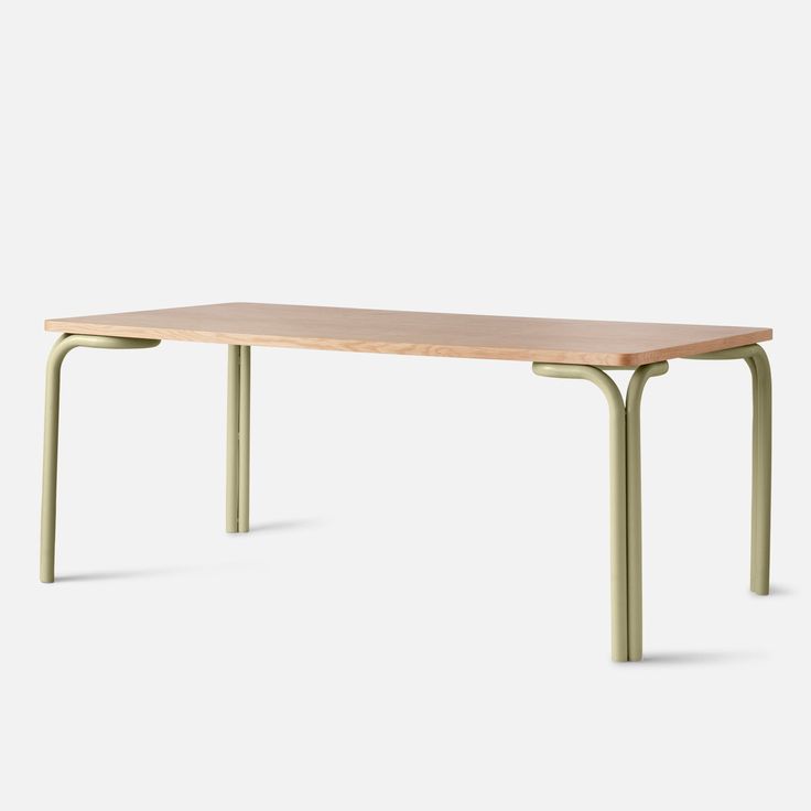 a wooden table sitting on top of a white floor next to a green metal frame