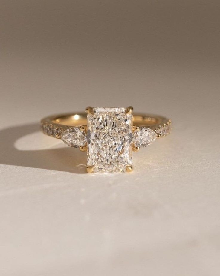 a diamond ring with three stones on the side and one stone in the middle, sitting on a white surface