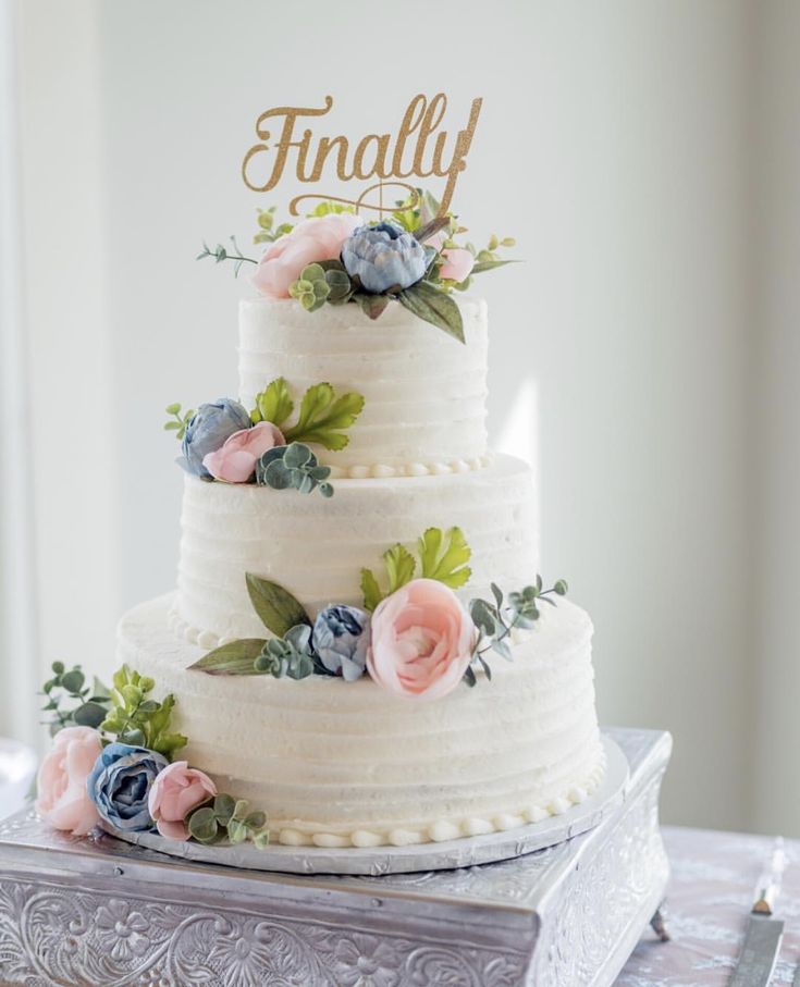 a three tiered cake with flowers and the word finally on top is sitting on a silver platter