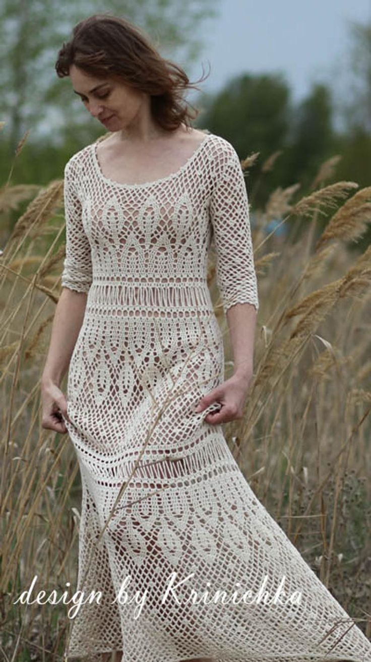 a woman in a white crochet dress walking through tall grass