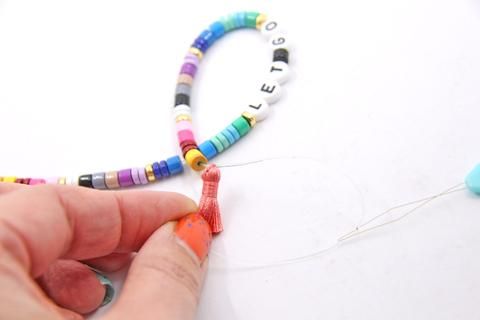 someone is making a beaded bracelet with beads