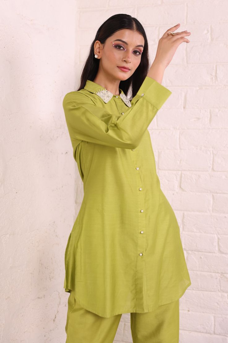 Elevate your wardrobe with this exclusive green cotton silk co ord set. Made from soft and breathable fabric, it offers a comfortable and relaxed fit that's perfect for any day wear. The solid plain design of the top and pants is simple yet stylish, featuring a shirt collar style with relaxed sleeves. Pair it with your favorite sneakers for a casual look or dress it up with some heels for a night out. With its high-quality material and excellent craftsmanship, this set will be your go-to outfit Cotton Silk Fabric, Shirt Collar Styles, Parrot Green, Green Tunic, Trouser Co Ord, Plain Tops, Plain Design, Silk Material, Pants Design