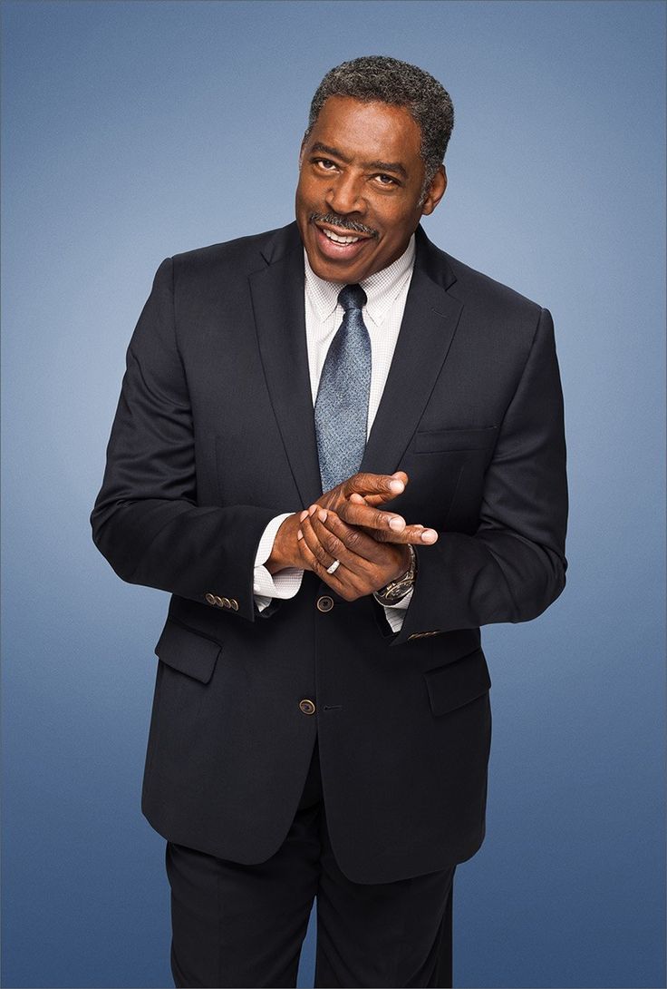 a man in a suit and tie is posing for a photo with his hands together