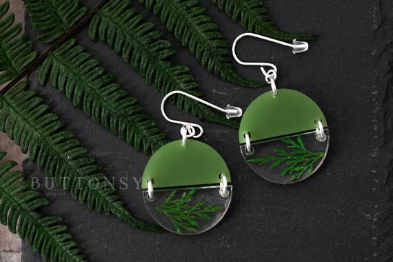 two green glass earrings with silver earwires hanging from them on a black surface