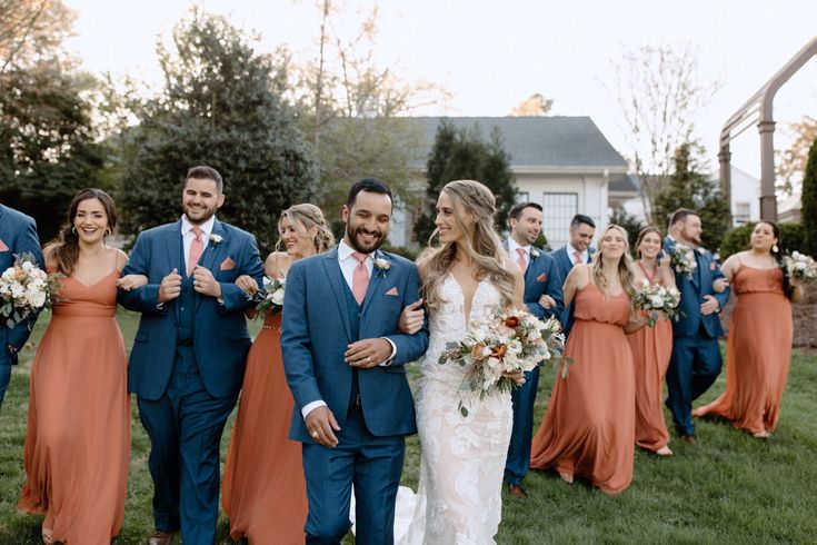 a bride and groom walking with their bridal party in front of the wedding venue