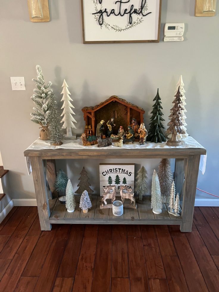 a christmas scene is displayed on top of a wooden shelf in the entryway to a house