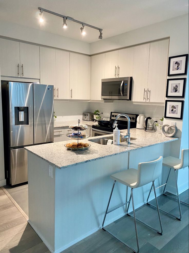 a modern kitchen with stainless steel appliances and white cabinets