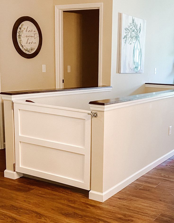 an empty kitchen with white cabinets and wood flooring in the middle of the room