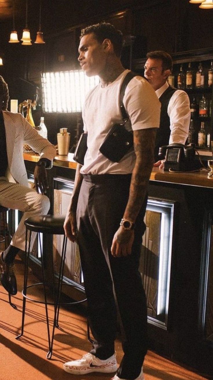 two men standing in front of a bar with bottles on the shelves and stools