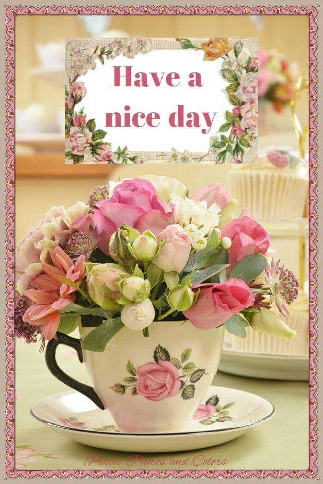 there is a cup with flowers in it and a sign that says have a nice day