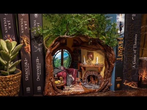 a book shelf with books and miniature figurines on it's shelves next to a potted plant