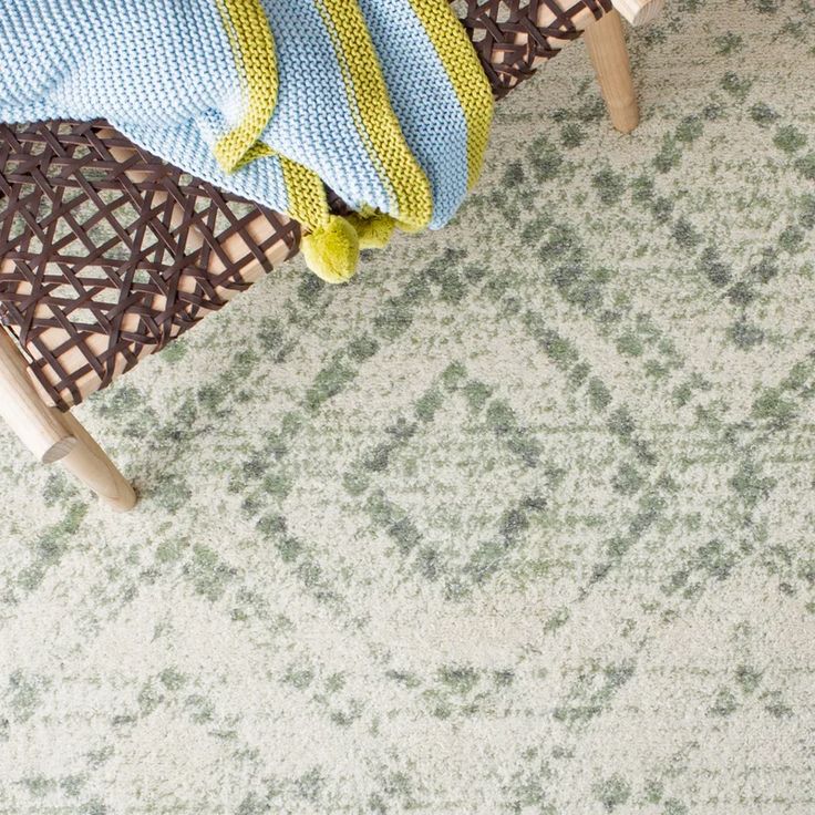 a chair with a blanket on top of it next to a rug that has green and blue designs