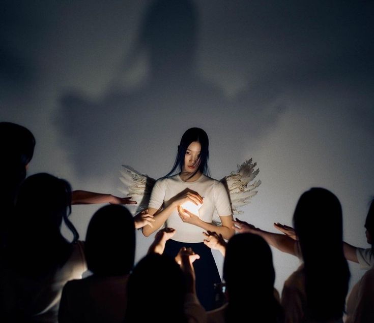 a group of people standing in front of a projection screen with angel wings on it