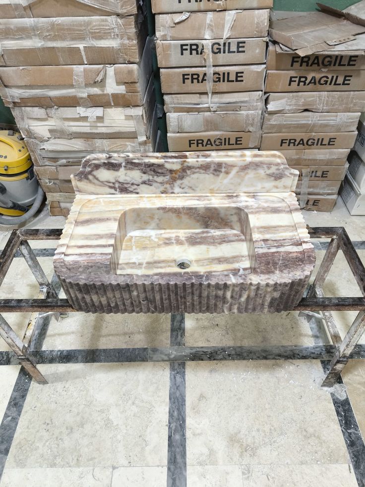 a table made out of metal and marble in a room with boxes on the floor