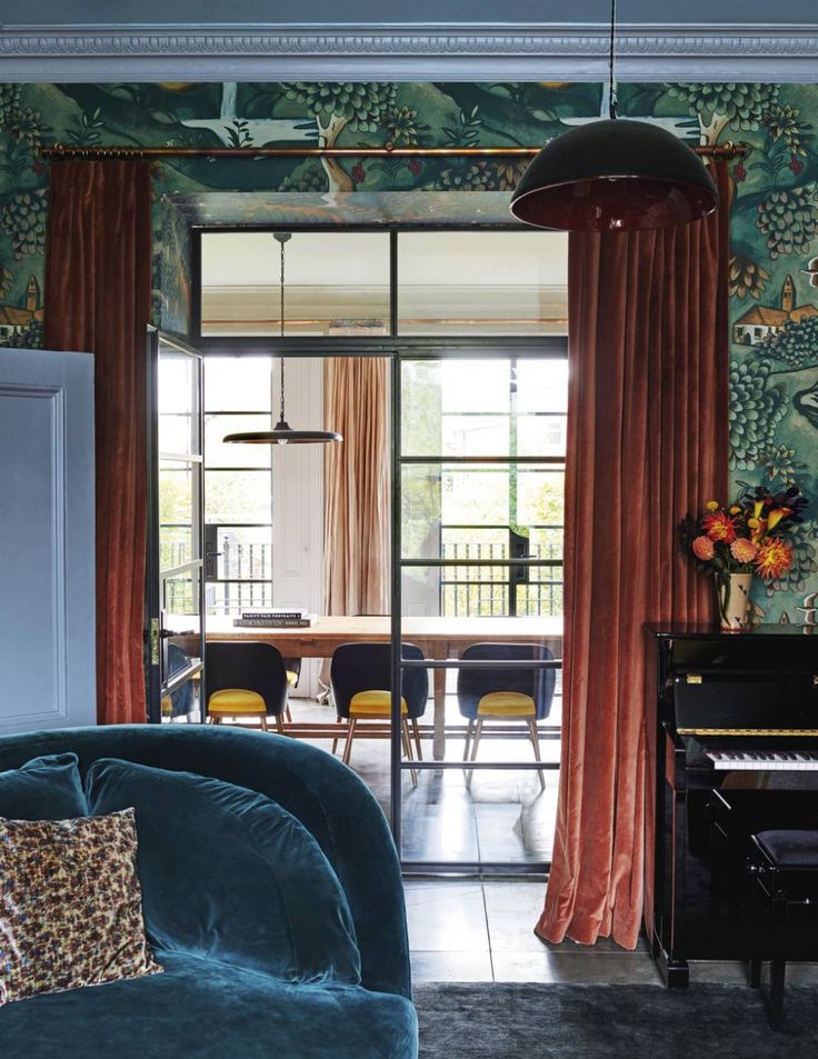 a living room filled with furniture and walls covered in colorful wallpaper, along with a piano