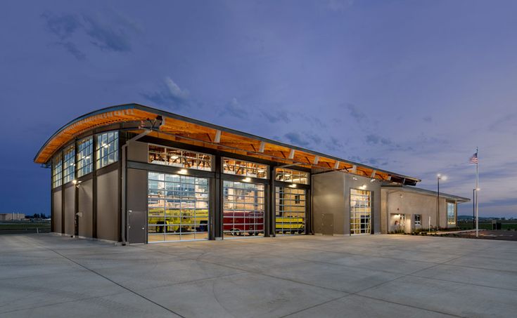 an empty parking lot in front of a building with a covered entrance at night time