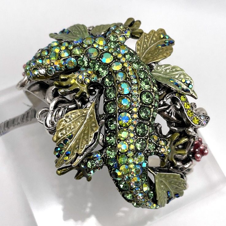 Kirks Folly Vault Couture Salamander Cuff Salamander Cuff - Silvertone/Average New with Tags GENUINE Signed Kirks Folly Covered in green aurora borealis crystals, this sparkling salamander cuff stands out with sophisticated shine. From Kirks Folly. Design Information - Green salamander encrusted with green aurora borealis crystals; salamander is draped across a bed of hand-enameled and stoned green leaves Product Details Color: Silvertone Size: Average Bracelet Measurements: Approx. 6-1/2"L x 2-5/8"W; 7-1/4 fit Metal Color: White Finish: Polished, oxidized Packaging: Boxed with pouch and romance card Imported Other Important Info - Due to the design elements of this bracelet, the fit and length measurements may vary; please order according to fit Green Bangle Cuff Bracelet For Party, Unique Green Cuff Bracelet Bangle, Unique Green Cuff Bangle Bracelet, Unique Green Bangle Cuff Bracelet, Green Salamander, Green Aurora Borealis, Bracelet Measurements, Green Aurora, Kirks Folly