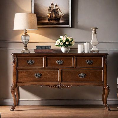 a wooden dresser sitting next to a lamp on top of a hard wood floor