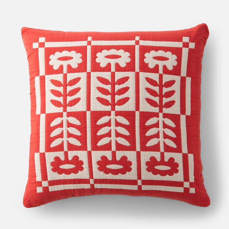 a red and white pillow with flowers on the front, in an embroidered pattern that has been