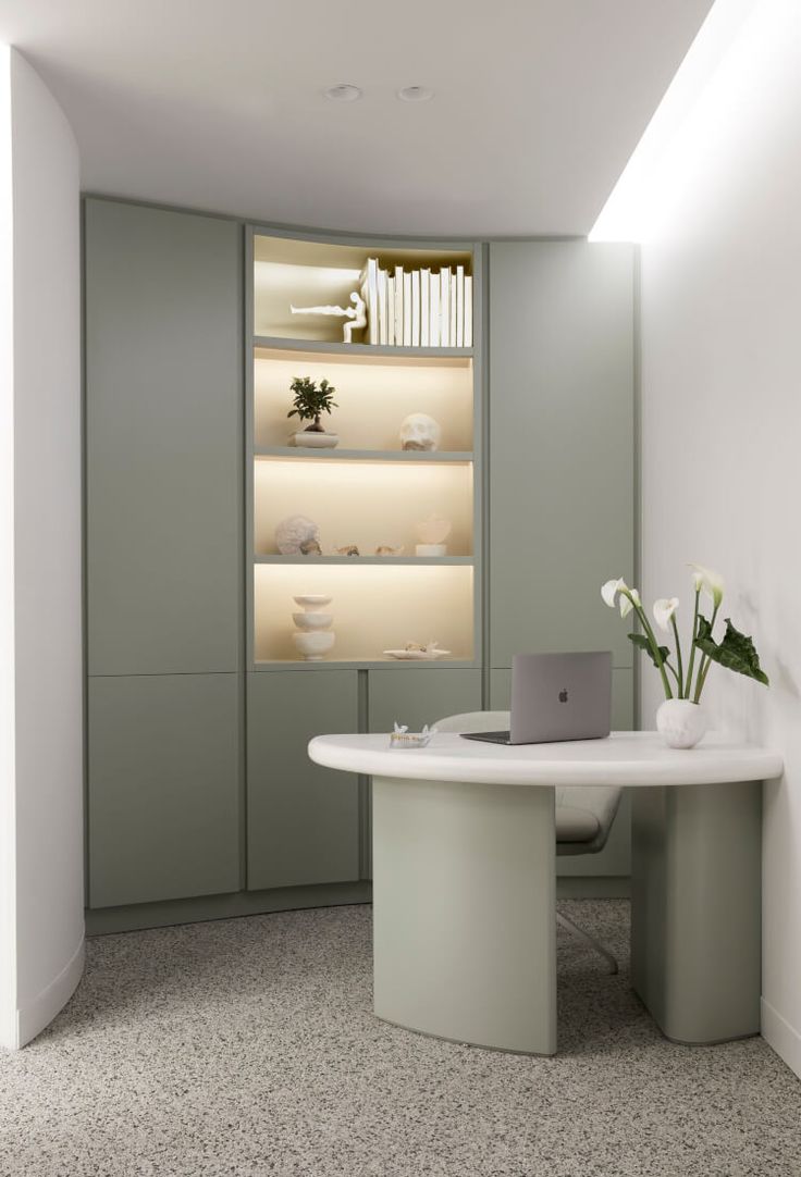 a room with a desk, shelves and flowers in vases on the wall next to it