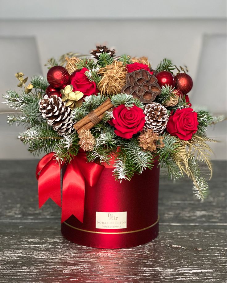 a christmas arrangement in a red box on a table