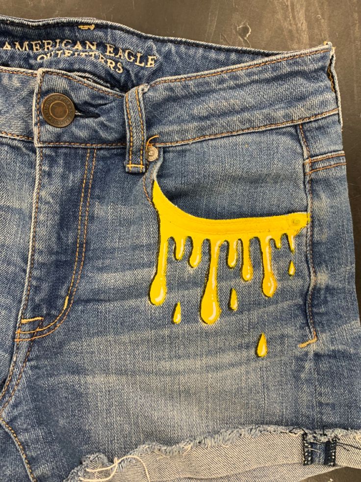 a pair of jeans with yellow drips on them