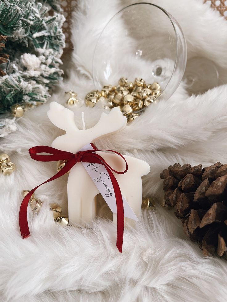 a white reindeer ornament sitting on top of a fur covered floor next to pine cones