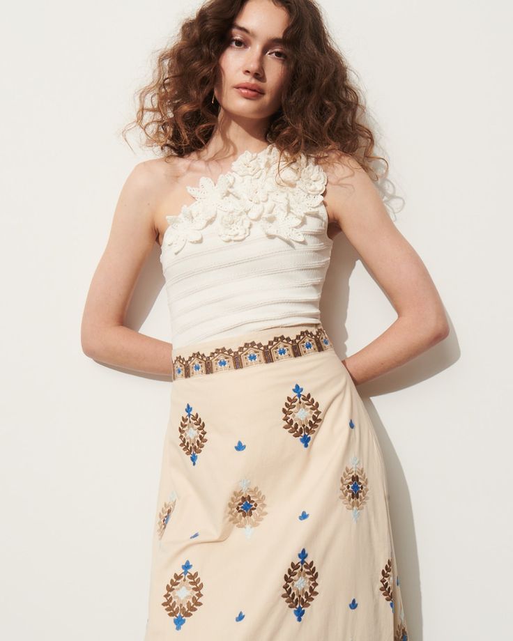 This soft a-line skirt is intricately embroidered in bold blue, rich tan, and soft sand coloring detailing a floral-inspired motif. Complement the high-rise waist with the matching top or a flowy t-shirt. Side-zip closure Length from Highest Point to Hem: 36 1/2" Detailed embroidery throughout Side slits Cotton Poplin Chic Floral Embroidery Dress With Flowy Skirt, Chic Dresses With Floral Embroidery And Flowy Skirt, Chic Floral Embroidery Flowy Dresses, Chic Dresses With Floral Embroidery, Chic Fitted Skirt With Floral Embroidery, Chic Floral Embroidered Skirt For Spring, Spring Embroidered Beige Skirt, Chic Spring Skirt With Floral Embroidery, Chic Floral Embroidery Skirt For Spring