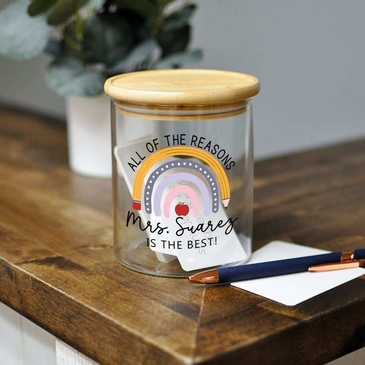 a glass jar sitting on top of a wooden table next to a pen and paper