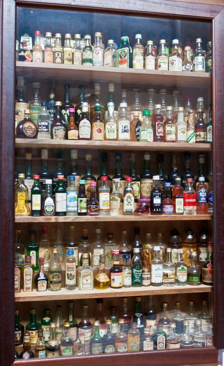 a wooden shelf filled with lots of different types of bottles and condiments on it