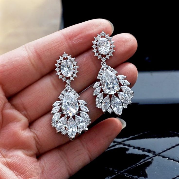 A delightfully unique pair of bridal earrings with an incredible sparkle! Adorned with flawlessly faceted cubic zirconia that capture the light in a dazzling array of sparkles, the earrings are rhodium plated for a bright finish which enhances the intricate detailing and conveys a modern take on old elegance. Overall length of the earring is 1.6" (approx. 4.2cm). Available in Silver, Rose Gold, Yellow Gold finishes and Silver with Blue stones for that "something blue" to match your individual st White Crystal Earrings With Diamond Accents, Pear-shaped Diamond Bridal Earrings With Sparkling Stones, Elegant Diamond Cut Cubic Zirconia Chandelier Earrings, Glamorous White Cubic Zirconia Chandelier Earrings, Elegant Cubic Zirconia Chandelier Earrings With Diamond Cut, Elegant Chandelier Earrings With Diamond Cut Cubic Zirconia, Glamorous Wedding Diamond Earrings With Accents, Dazzling Diamond White Crystal Bridal Earrings, Dazzling Crystal Dangle Bridal Earrings