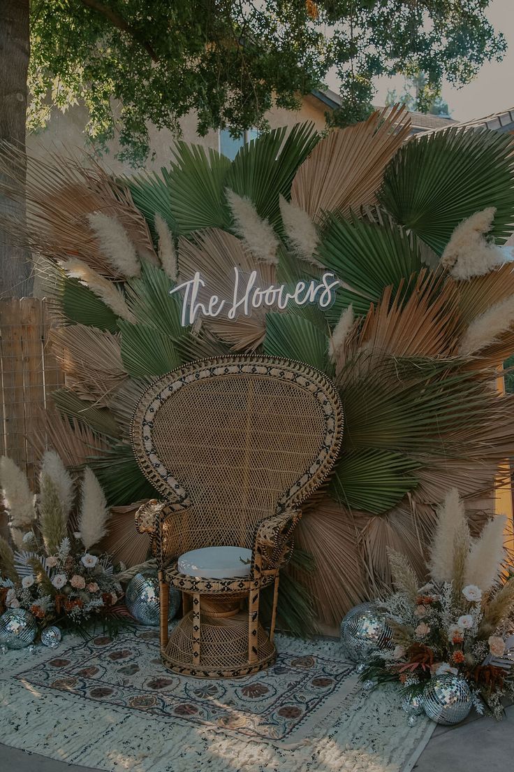 a wicker chair sitting on top of a rug next to a wall covered in palm leaves