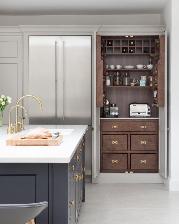 an open cabinet in the middle of a kitchen with white countertops and gray cabinets