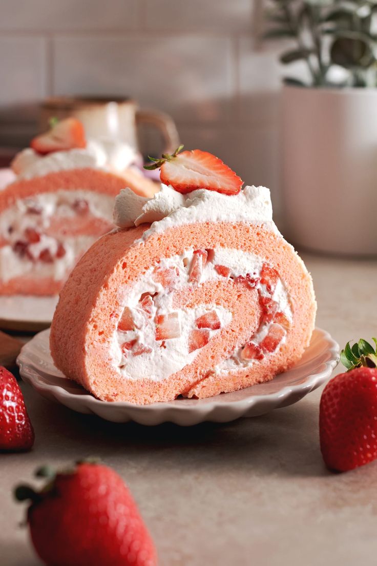 a strawberry roll is on a plate with strawberries around it and the cake has been cut in half