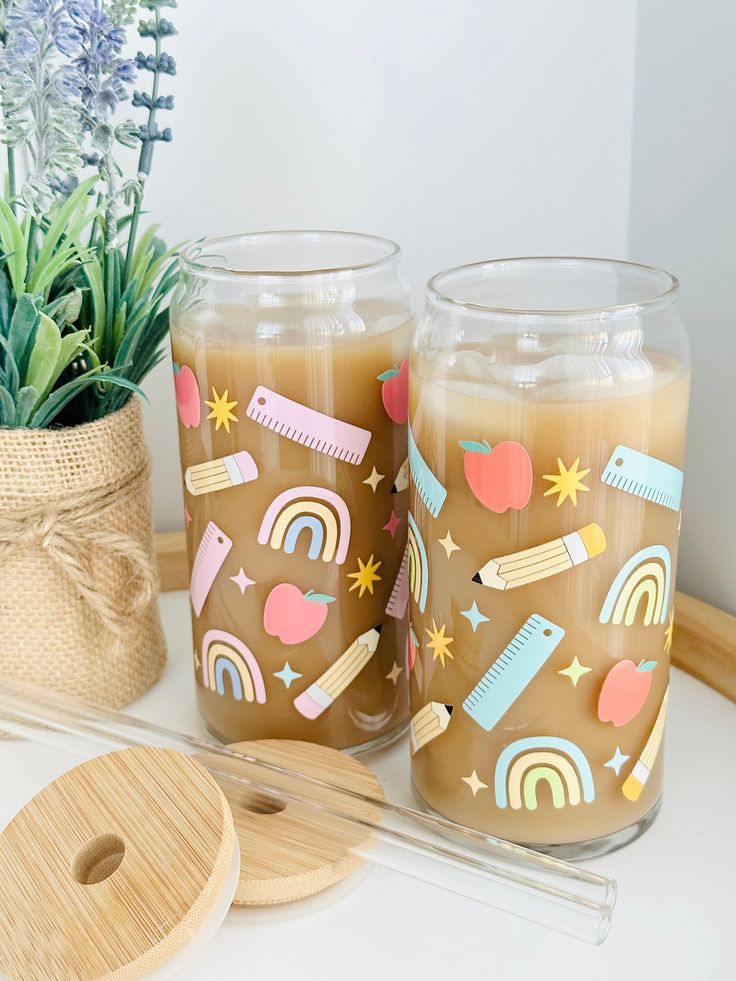 two candles sitting on top of a table next to a potted plant and some scissors