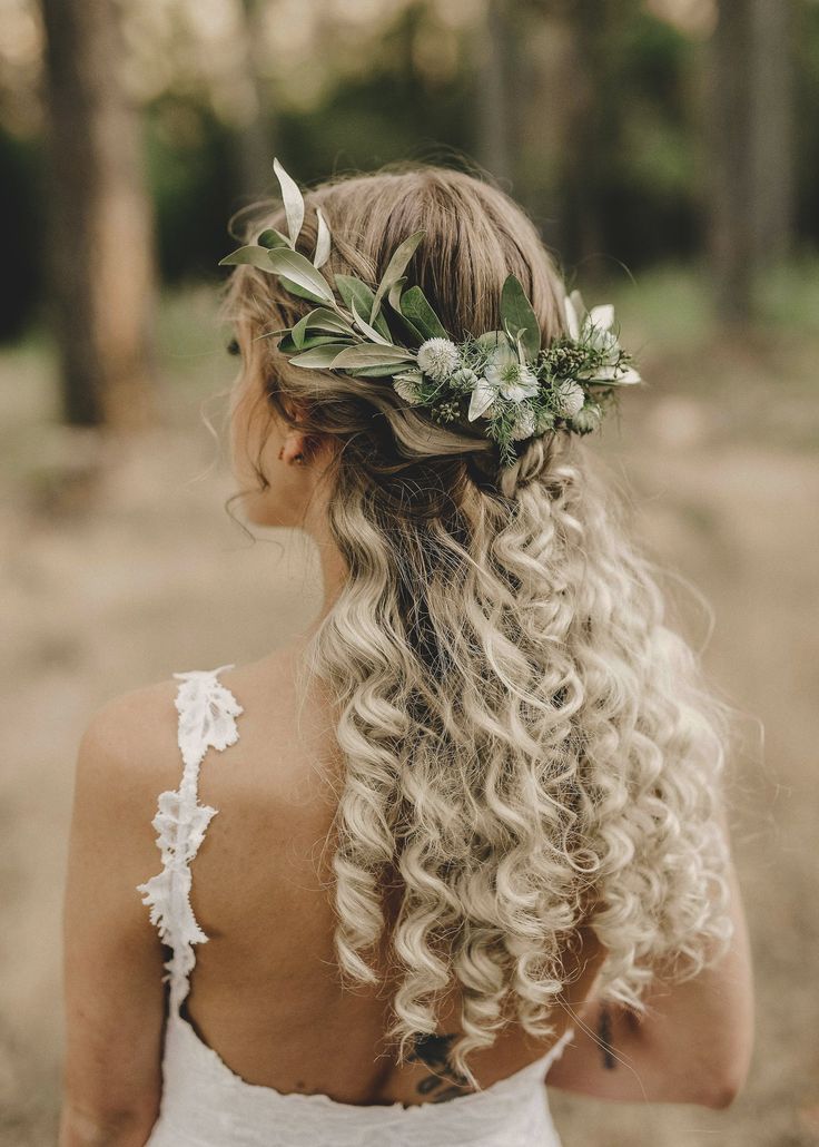 a woman with long blonde hair wearing a flower crown in her hair, looking down at the ground