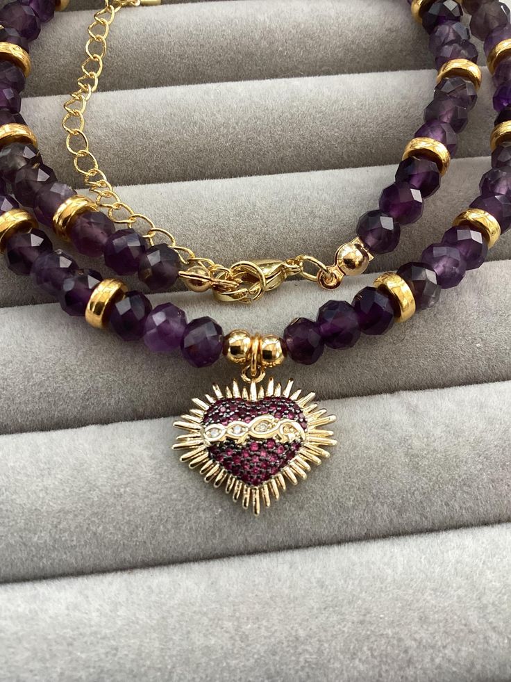 Item details Elevate your jewelry collection with our Sacred Heart amethyst necklace. Embrace the mystical beauty of this 16k Gold Plated pendant featuring Religious Mexican Milagros design and a natural Purple stone. This crystal choker is a stunning tribute to the Heart Of Jesus. Make a statement with this unique piece of Jewellery. I have used faceted rondelle amethyst beads  6 mm, to create this soft purple necklace. Varied shades of purple to create this sparkling Beaded Necklace Sacred Hea Spiritual Gemstone Beads Jewelry For Valentine's Day, Purple Round Beaded Jewelry For Mother's Day, Amethyst Birthstone Heart Pendant Jewelry, Amethyst Gemstone Jewelry For Valentine's Day, Heart-shaped Amethyst For Jewelry Making, Heart Shaped Amethyst For Jewelry Making, Valentine's Day Amethyst Gemstone Jewelry, Purple Amethyst Jewelry With Heart Charm, Purple Gemstone Jewelry For Valentine's Day